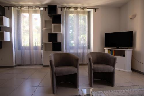 a living room with two chairs and a flat screen tv at Griante suites in Griante Cadenabbia