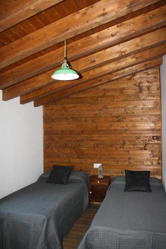 two beds in a room with wooden walls at Casa Rural Avellaneda in Avellaneda