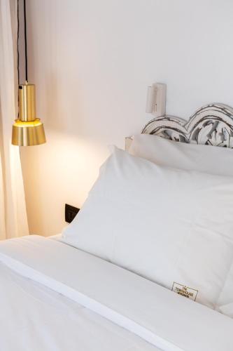 a white bed with white pillows and a lamp at The TownHouse Mykonos in Mikonos