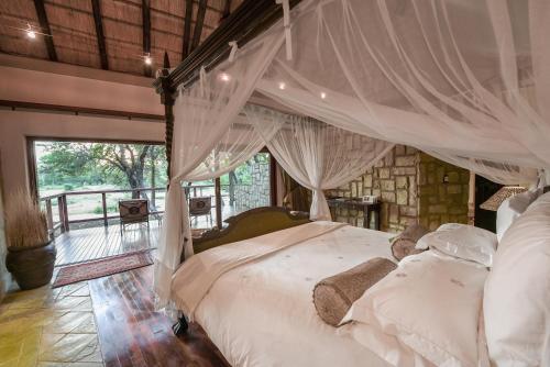 a bedroom with a bed with a canopy at Shumbalala Game Lodge in Thornybush Game Reserve