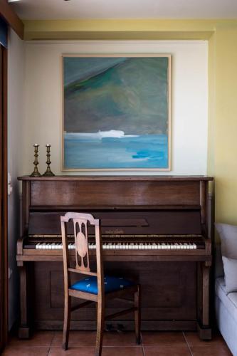 a piano in a room with a chair and a painting at Dolichi View in Pythagoreio