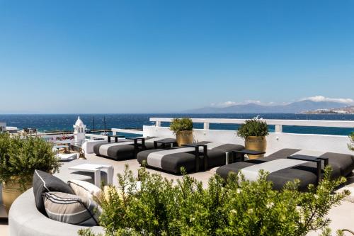 a rooftop patio with black and white furniture and the ocean at The TownHouse Mykonos in Mýkonos City