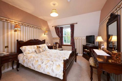 a bedroom with a bed and a desk and a television at The Prince's House Hotel in Glenfinnan