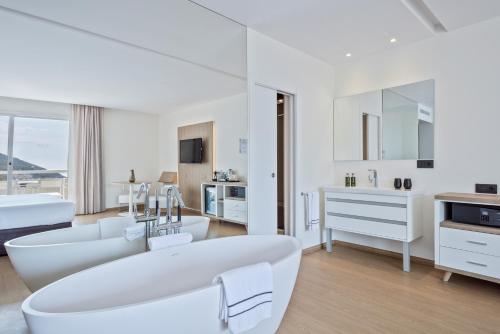 sala de estar blanca con sofá blanco y bañera en Melia Sitges en Sitges