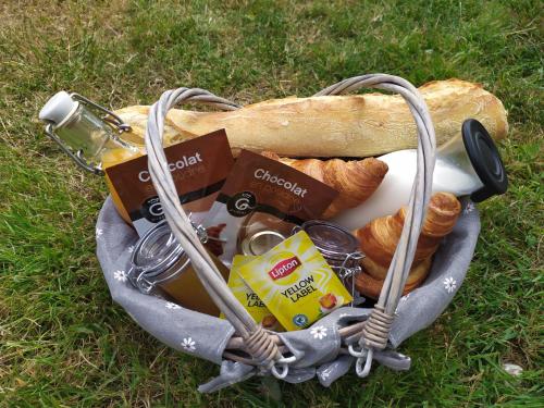 a basket filled with bread and drinks and a bagel at Studio Les chambres de la source - Milouin in Sancourt