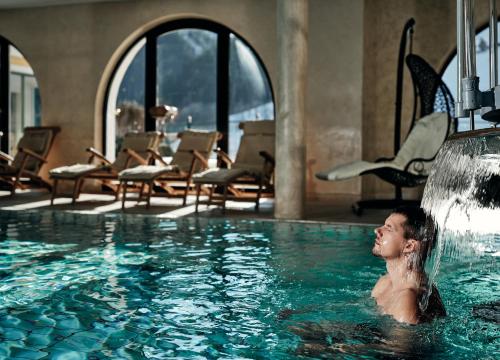 a man in a swimming pool with a waterfall at Hotel Pichlmayrgut in Schladming