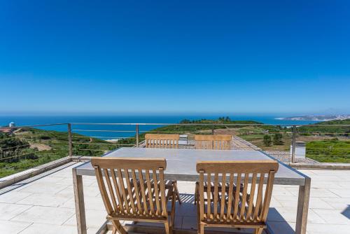 a table and chairs on a patio with a view of the ocean at Casas da Pescaria A in Nazaré