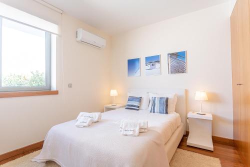 a white bedroom with a bed and a window at Casas da Pescaria A in Nazaré