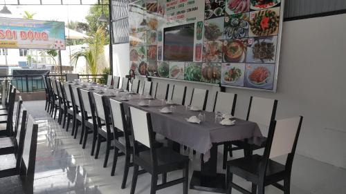 une longue table dans un restaurant avec des chaises et un panneau dans l'établissement Muine Sports Resort, à Phan Thiết