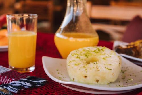 een bord met een donut en een glas sinaasappelsap bij Pousada Avenida in Monte Verde