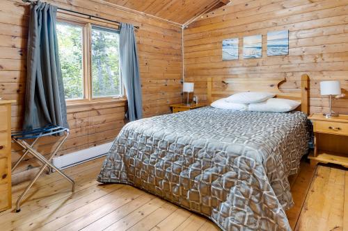 um quarto com uma cama num chalé de madeira em Ingonish Chalets em Ingonish Beach