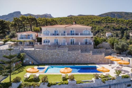 a villa with a swimming pool and orange umbrellas at PENNY LUXURY APARTMENTS in Kokkari