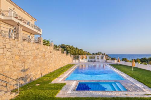 a villa with a swimming pool next to the ocean at PENNY LUXURY APARTMENTS in Kokkari