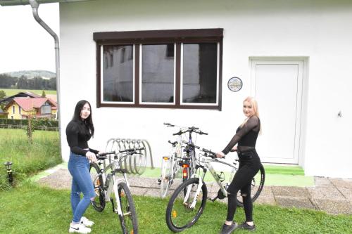 duas mulheres de pé com as suas bicicletas em frente a uma casa em Apartment Rappitsch em Sankt Marein bei Knittelfeld