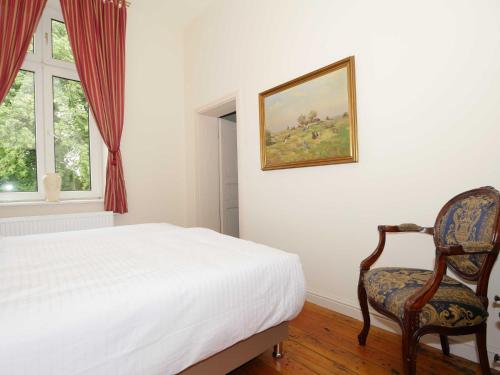 a bedroom with a bed and a chair next to a window at Schlosshotel Gross Koethel in Hohen Demzin
