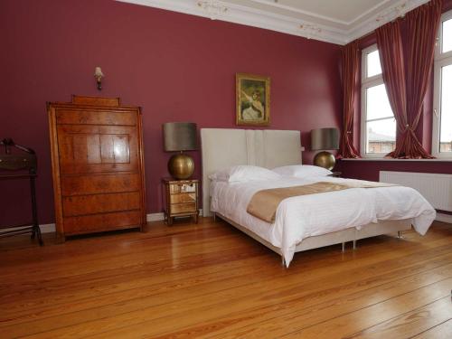 a bedroom with a large bed and red walls at Schlosshotel Gross Koethel in Hohen Demzin