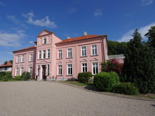 una gran casa rosa con una entrada delante de ella en Schlosshotel Gross Koethel, en Hohen Demzin