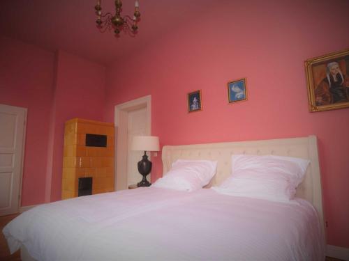 a bedroom with a white bed with a pink wall at Schlosshotel Gross Koethel in Hohen Demzin