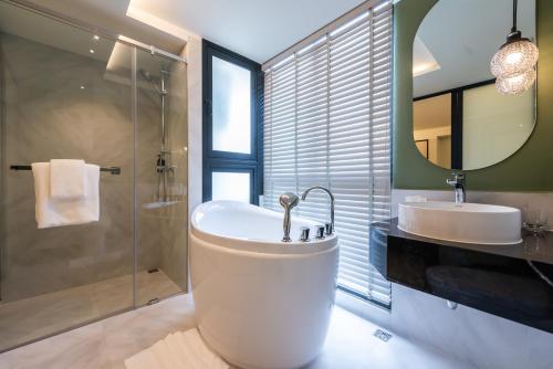 een badkamer met een bad, een wastafel en een spiegel bij Kaya Heritage Hotel in Bangkok