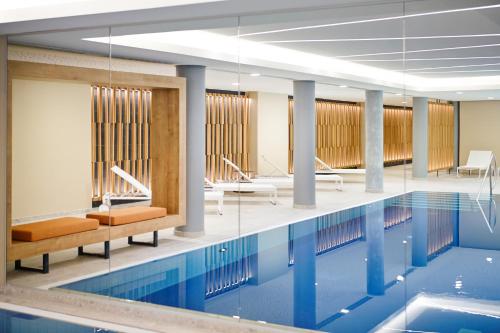 - une piscine avec des chaises et des tables dans un bâtiment dans l'établissement Novotel München City, à Munich
