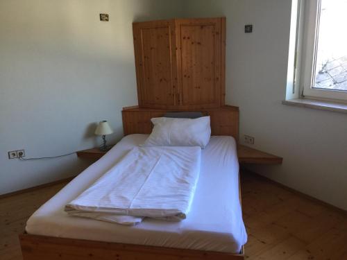 1 dormitorio con 1 cama con sábanas blancas y ventana en Wein4tel-Apartments, en Auersthal