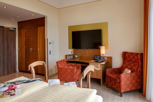 a hotel room with a bed and a desk and a television at Recknitztal-Hotel Marlow in Marlow