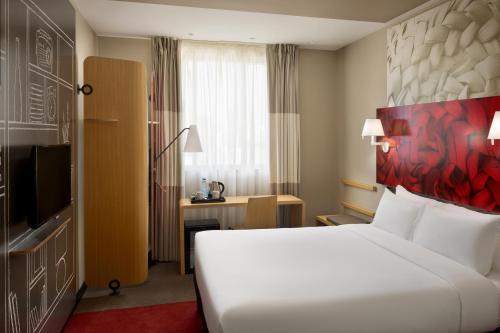 Habitación de hotel con cama blanca y escritorio en ibis Jeddah City Center, en Yeda