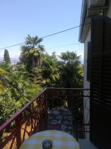 een balkon met een tafel en stoelen en palmbomen bij Romantic room with balcony in Lovran