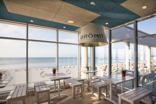 a restaurant with tables and chairs and a view of the ocean at aja Grömitz in Grömitz