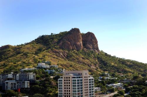 a mountain in front of a city with a building at Hotel Grand Chancellor Townsville in Townsville