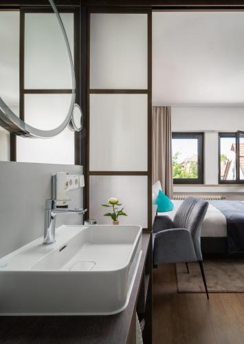 a bathroom with a sink and a bed and a mirror at Hetzel Hotel Stuttgart in Stuttgart