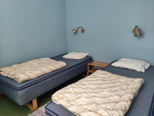 Stuga Ekesberget Stugby في Ekshärad: سريرين في غرفة بجدران زرقاء