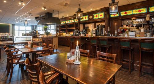 a restaurant with wooden tables and chairs and a bar at Fletcher Hotel-Restaurant De Broeierd-Enschede in Enschede