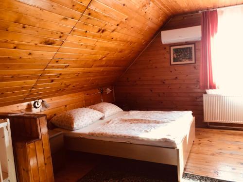 um quarto com uma cama num quarto de madeira em Lellei Pihenőház Balatonlelle em Balatonlelle