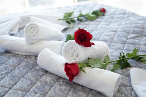 a group of white towels with a rose on a bed at The Era Otel in Gölhisar