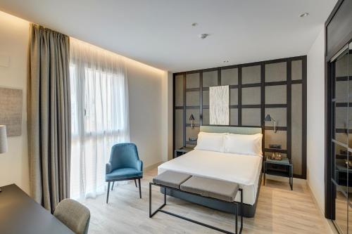 sypialnia z łóżkiem i niebieskim krzesłem w obiekcie Sercotel Ayala w mieście Bilbao