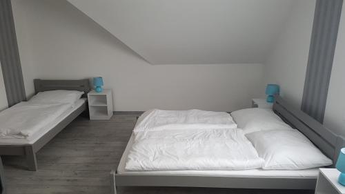 two beds in a room with white walls at Domb Apartmanok in Sukoró