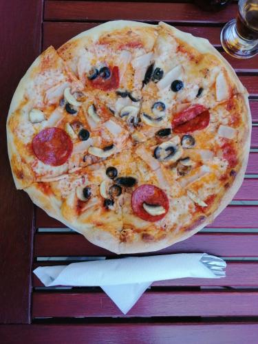 a pizza with pepperoni and mushrooms on a table at Pensiunea Daria in Fundata