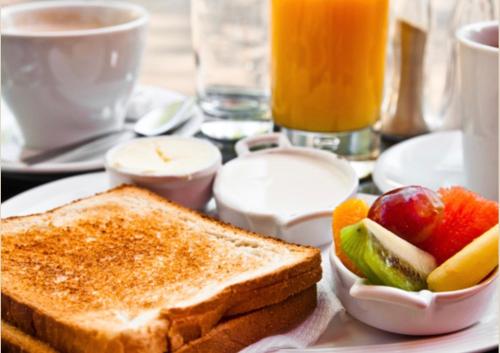 a white plate with toast and fruit on a table at Motel Você Que Sabe (Adult Only) in Curitiba