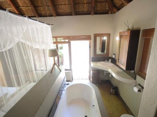 a bathroom with a large tub and a sink at 11 Raptors Lodge in Hoedspruit