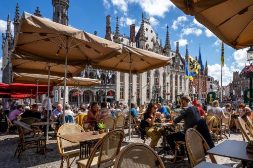 a group of people sitting at tables in front of a building at Hotel Central in Bruges