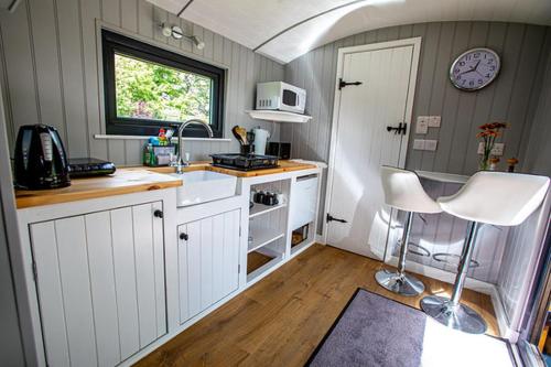 a small kitchen with white cabinets and a window at Woodpeckers in Llandrindod Wells