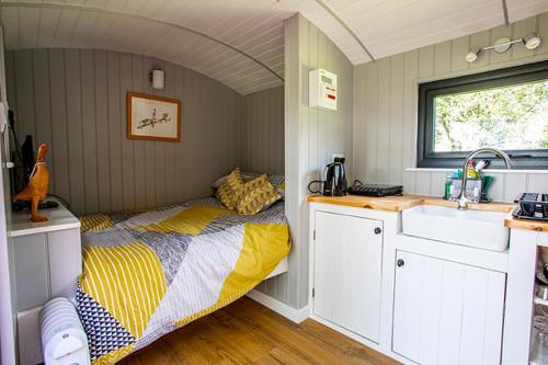 um pequeno quarto com uma cama e um lavatório em Woodpeckers em Llandrindod Wells