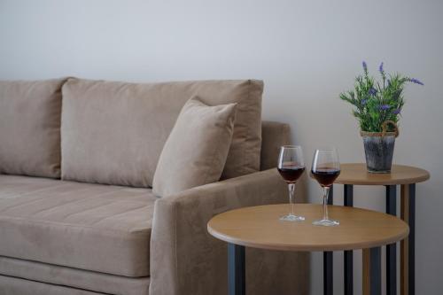 Twee glazen wijn staan op tafels voor een bank. bij BISALTAE SEASIDE SUITES in Keramotí