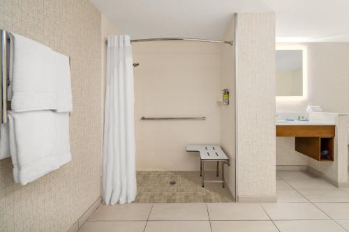 baño con ducha y banco. en Holiday Inn Express Cruise Airport, an IHG Hotel, en Fort Lauderdale