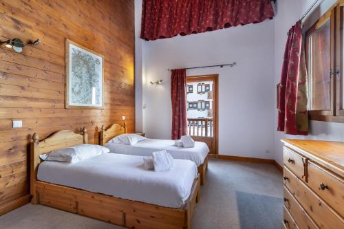 Duas camas num quarto com paredes de madeira em Les Suites du Val Claret em Tignes