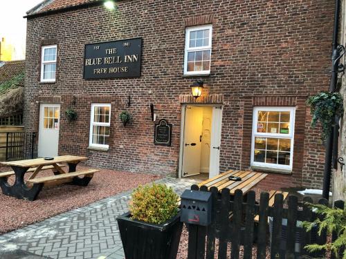 un edificio de ladrillo con una mesa de picnic delante de él en The Blue Bell Crookham en Cornhill-on-tweed