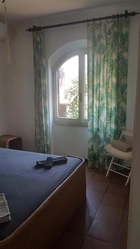 1 dormitorio con cama, ventana y silla en villa Clody san felice circeo, en San Felice Circeo