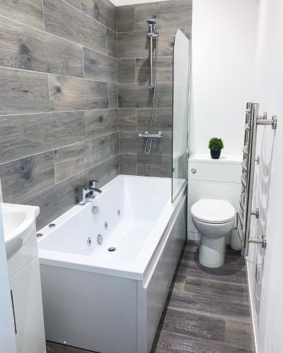 a bathroom with a white tub and a toilet at Albert Hottub & Jacuzzi Apartments in Blackpool