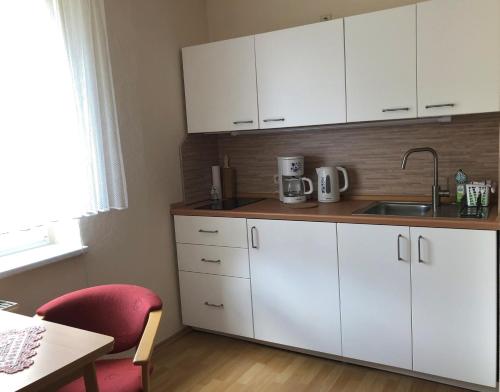 a kitchen with white cabinets and a sink and a table at Ferienwohnung Buschbeck in Marienberg